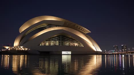 dubai opera reflecting beautifully on the surface of an artificial lake at night, surrounded by vibrant city lights and a stunning skyline, creating a captivating urban scene