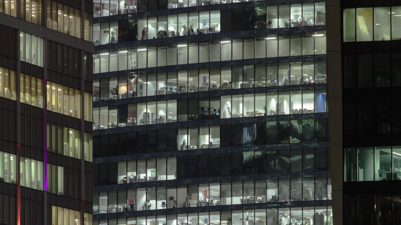 Vista cercana a las ventanas de oficinas en los rascacielos del Centro Internacional de Negocios de la Ciudad de noche, timelapse desde arriba