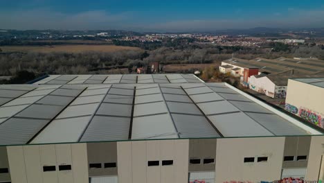 large industrial warehouse roof with the landscape of abrera, barcelona in the background, aerial view