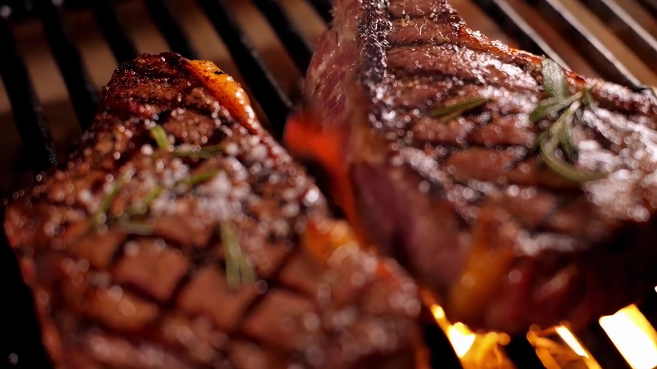 Two Juicy Steaks Grilling Over Open Flames