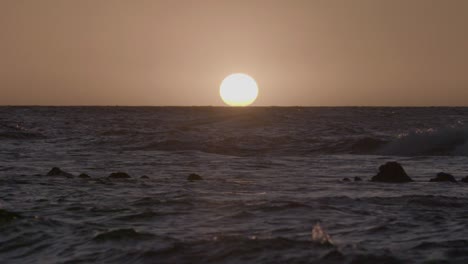 looking out onto the ocean as waves roll across the setting sun in hawaii