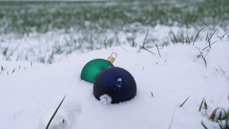 close up shot of christmas balls falling into snow outdoors in nature during winter