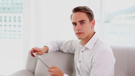 serious young man using his tablet sitting on couch