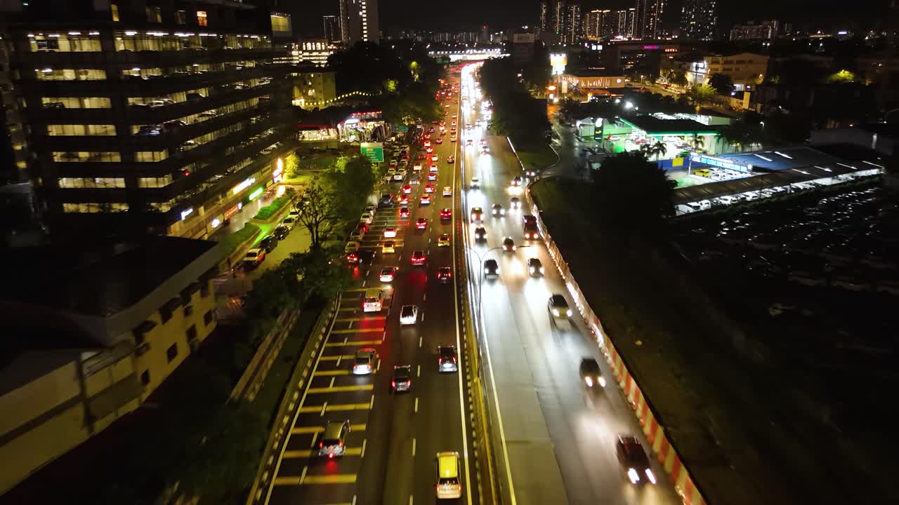 A push-in drone shot of the nighttime traffic flowing through Kuala Lumpur, Malaysia, showcases the city's vibrant urban infrastructure, moving vehicles, and illuminated roadways. UHD.