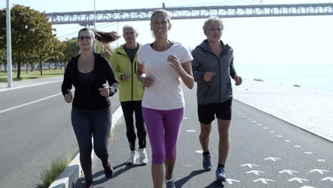 active mature joggers running on promenade near the river