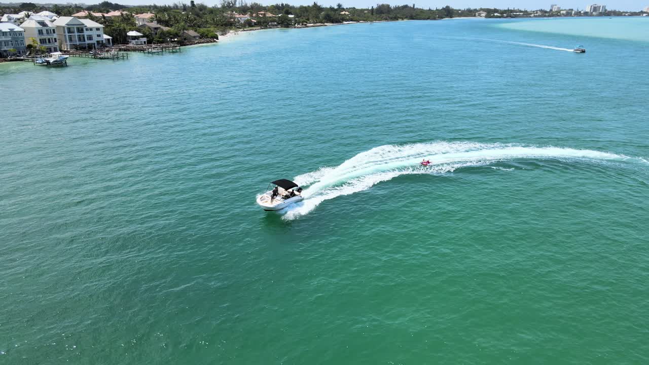 풍선 튜브에서 사람들을 끌어들이는 바다에서 보트를 따라