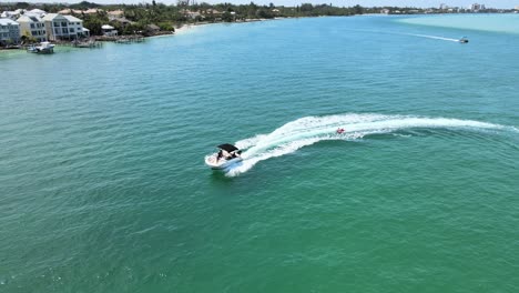 Einem-Boot-Im-Meer-Folgen,-Das-Menschen-Auf-Einem-Aufblasbaren-Schlauch-Zieht