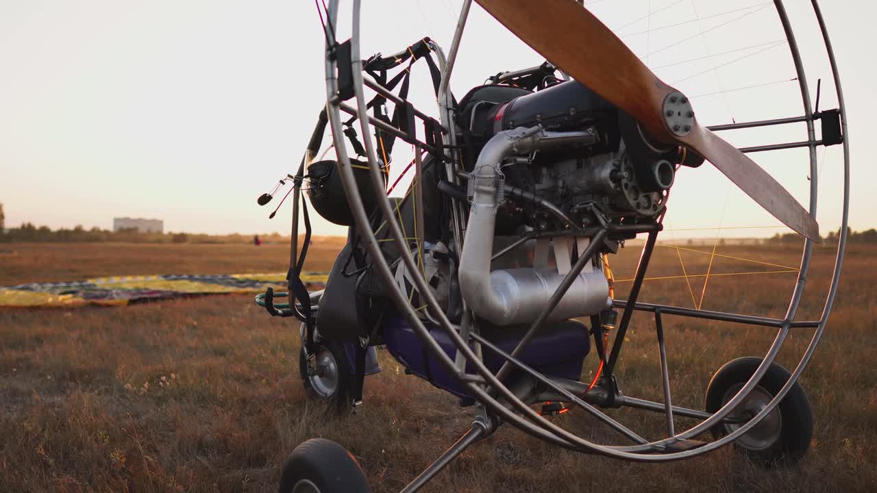 el parapente de motor se encuentra en el aeropuerto en los rayos de la luz del atardecer. la cámara se mueve a lo largo de la órbita