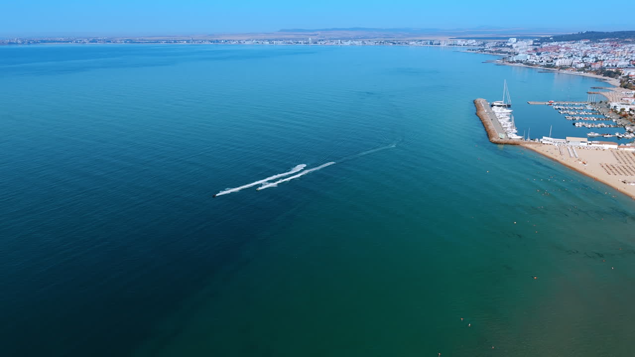 Two jet ski scooters ride by the blue waterscape. Fun water sport activities in summer at the seaside. Aerial view