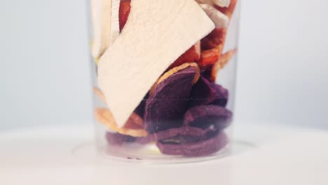 a transparent plastic container filled with colorful slices of freeze-dried carrots and beets, showcasing their vibrant orange, yellow, and purple hues. ideal for snacking or cooking.