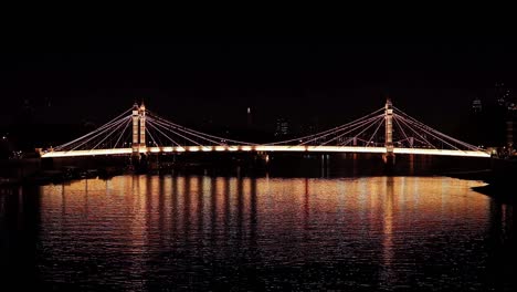 albert bridge, london, illuminated at night and reflected in the river thames