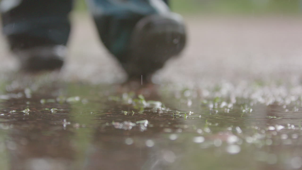 SLOW MOTION - A child stomps in a muddy puddle as they walk through