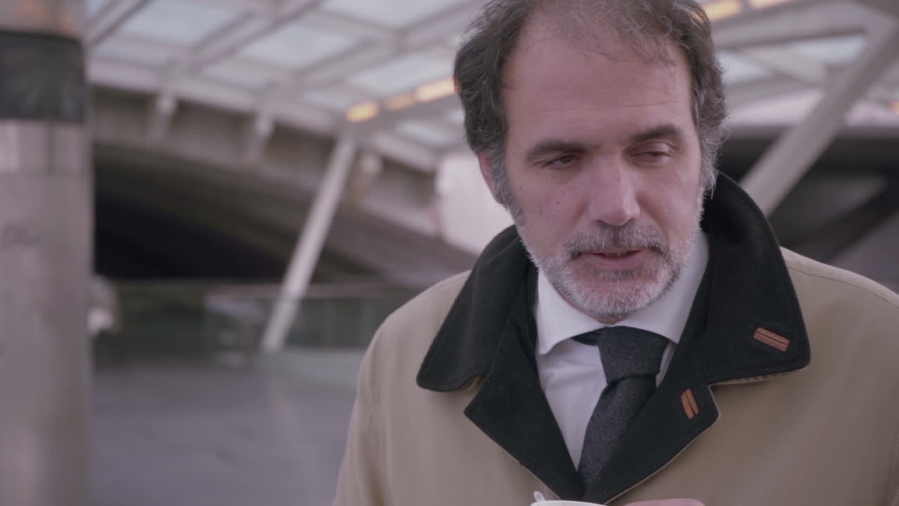 зрелый бородатый мужчина пьет кофе и курит сигарету в замедленном движении