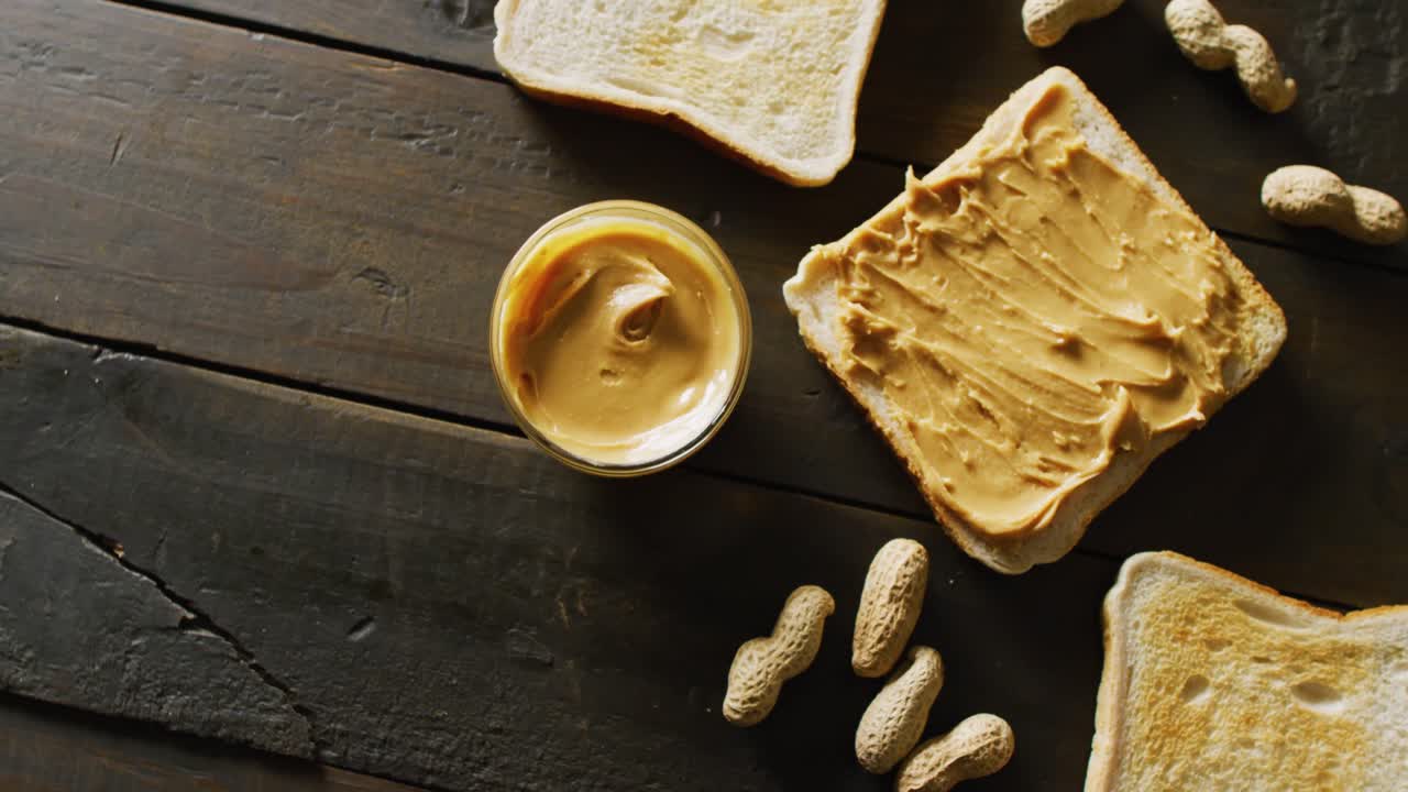 나무 배경 에 땅콩 버터 를 넣은 토스트 의 클로즈업 비디오
