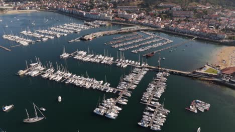 aerial - marina view with boats moored in baiona, spain, adjacent sandy beach with clear water