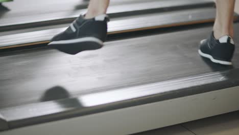 Closeup-feet-running-back-on-treadmill-in-fitness-gym.