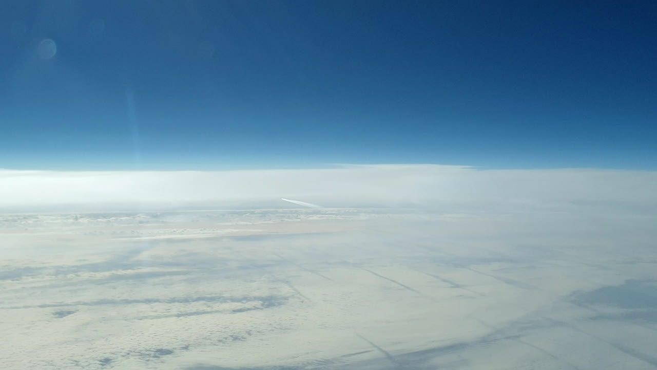 vista increíble desde la cabina de un avión que vuela alto por encima de las nubes dejando un largo rastro de aire de vapor de condensación blanco en el cielo azul