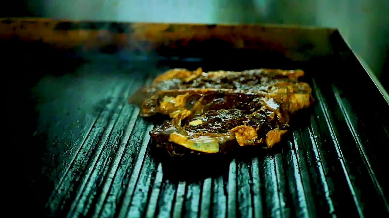 Meat sizzling on a grill with smoke cooking in slow motion, orbit shot