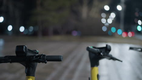 vista en primer plano de las manijas de las bicicletas eléctricas estacionadas con efectos bokeh suaves en el fondo, y vista borrosa de una casa
