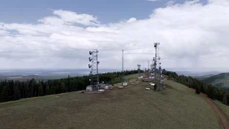 communication towers at the mountain top in greens peak, arizona surrounded by lush trees - aerial drone