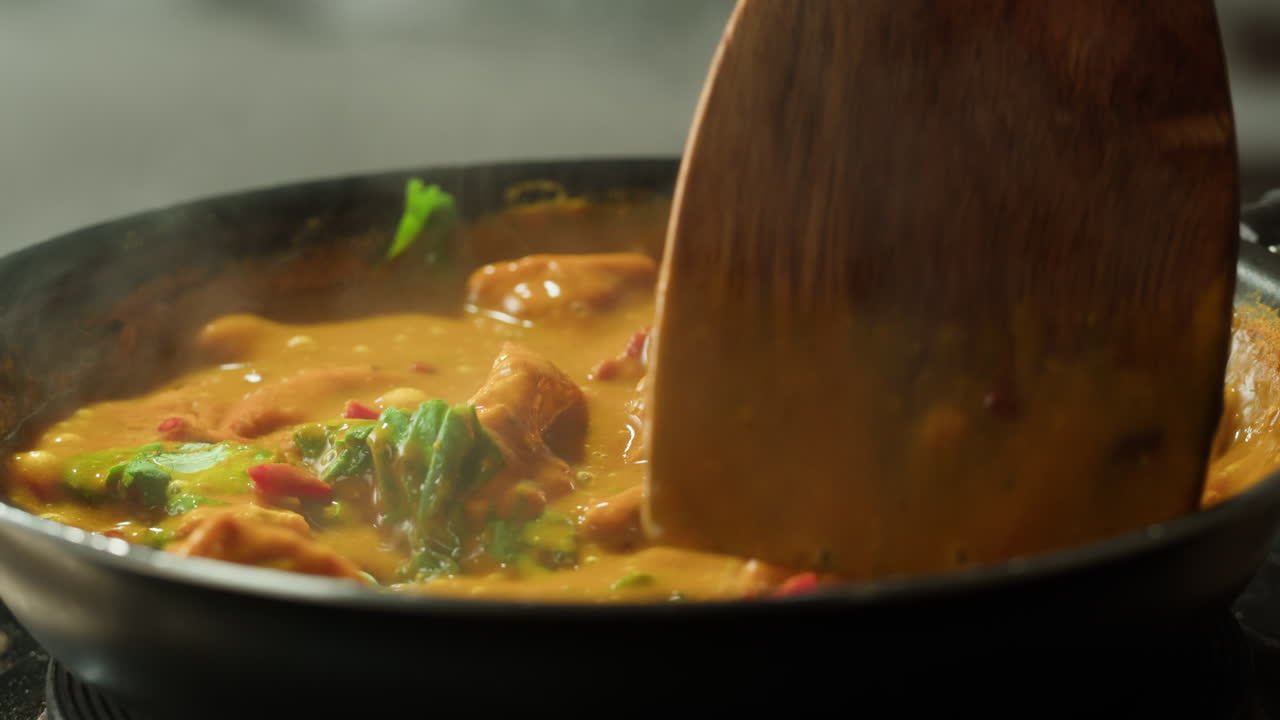 Yellow boiling sauce on pan close-up. Asian cuisine concept. Curry is a dish with a sauce seasoned with spices. Curries may contain fish, meat, poultry, or shellfish, either alone or in combination with vegetables. Others are vegetarian.