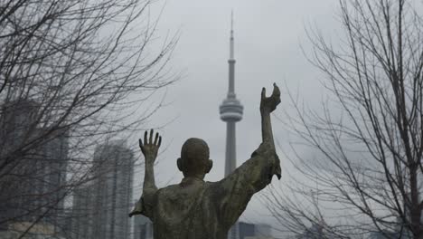 jubilant man statue in foreground of cn tower on cloudy day in toronto