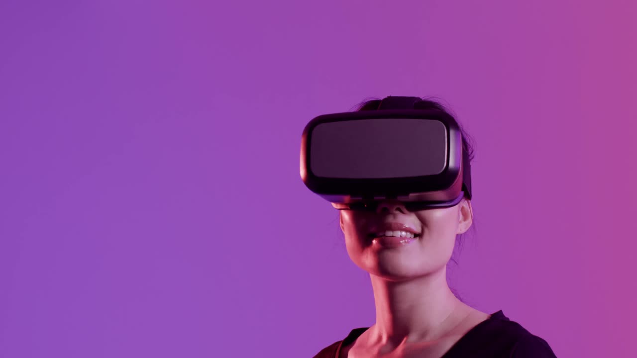 Happy asian woman using vr headset on purple background with copy space, slow motion