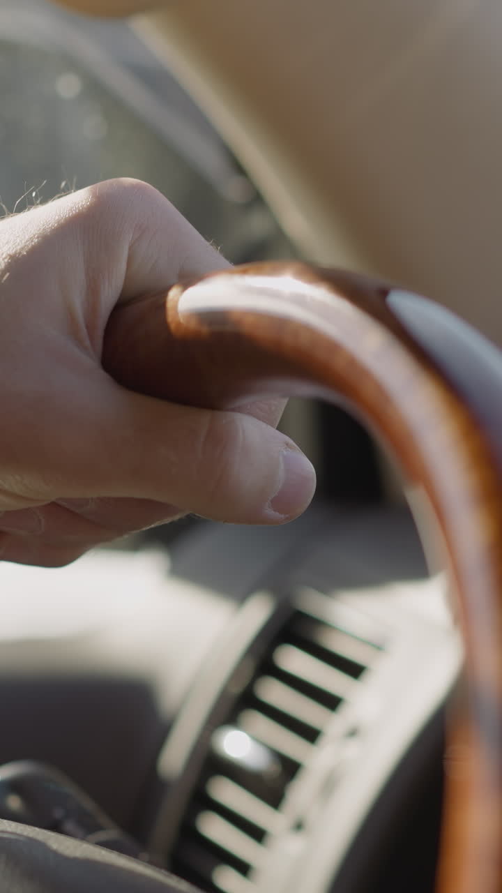 Young man with digital wristwatch drives auto along road on sunny day closeup. Driver has ride by comfortable car along city street. Modern vehicle