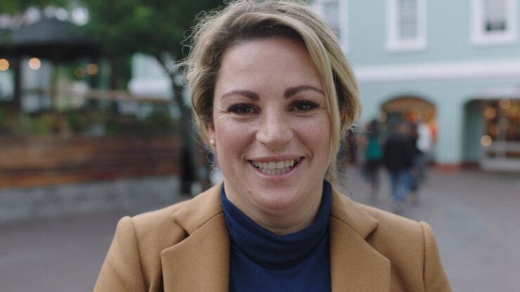 ritratto al rallentatore di una elegante donna d'affari bionda in abito che ride allegra alla telecamera sullo sfondo urbano