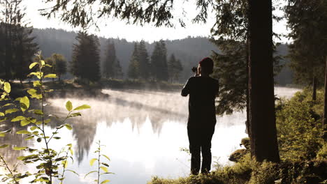 landscape photographer taking pictures at lake caumasee, switzerland on a misty morning