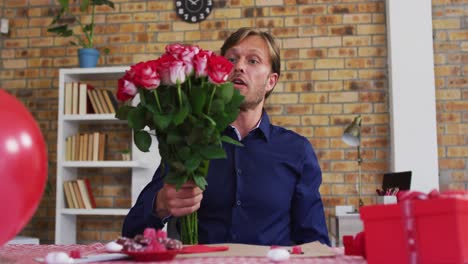 retrato de un hombre caucásico que muestra un ramo de flores en una videollamada en casa