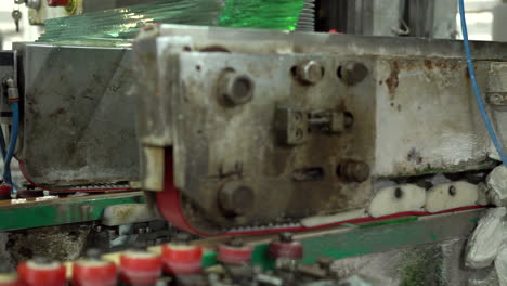 Worker-in-the-red-shirt-working-behind-an-industry-machine-for-smoothing-glass-panels-edges-in-old-factory