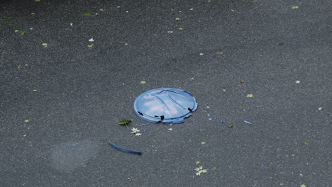 la tapa de la papelera es atropellada en la calle por un auto durante una tormenta
