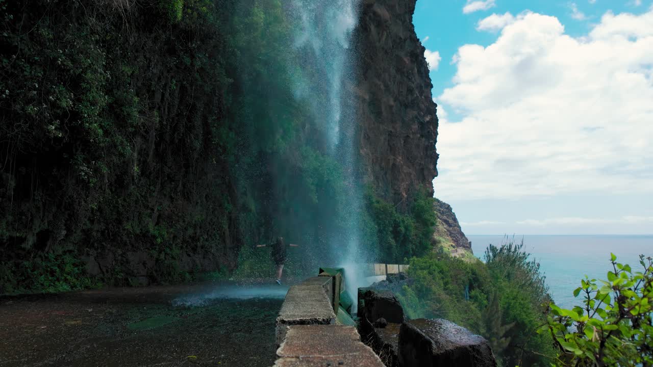 Cascada dos Anjos, waterfall on a road in Madeira island, Portugal, with woman next to it