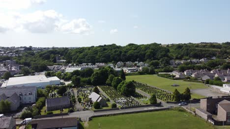 Small-church-graveyard-in-rural-Welsh-Llangefni-village-aerial-view-flying-across-scenic-woodland-countryside-community