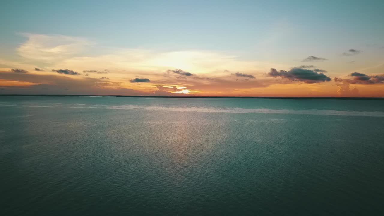 Incredibile ripresa drone che arretra e scende lentamente di un perfetto tramonto paradisiaco verso una spiaggia da sogno.