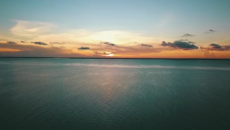 increíble toma de dron hacia atrás que se hunde lentamente de una perfecta puesta de sol paradisíaca en una playa de ensueño