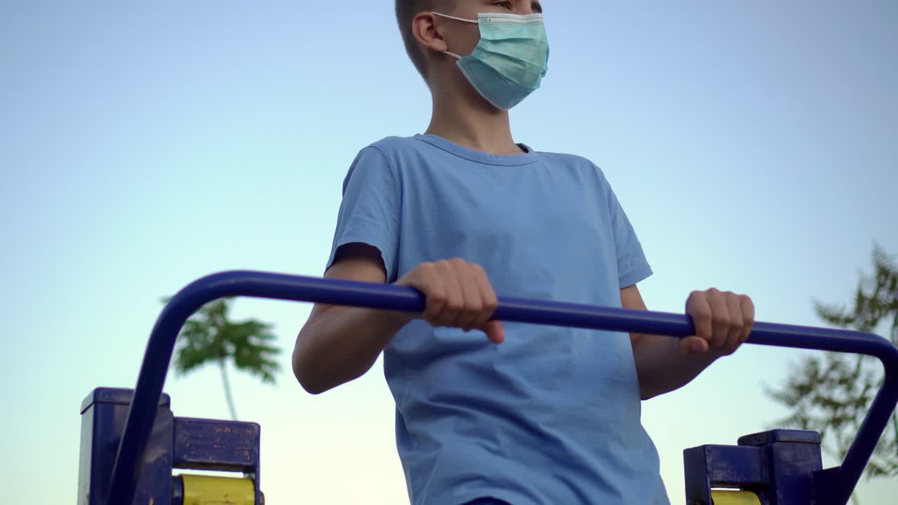 의료 마스크를 입은 십대 소년이 스포츠에 종사하고 있습니다.