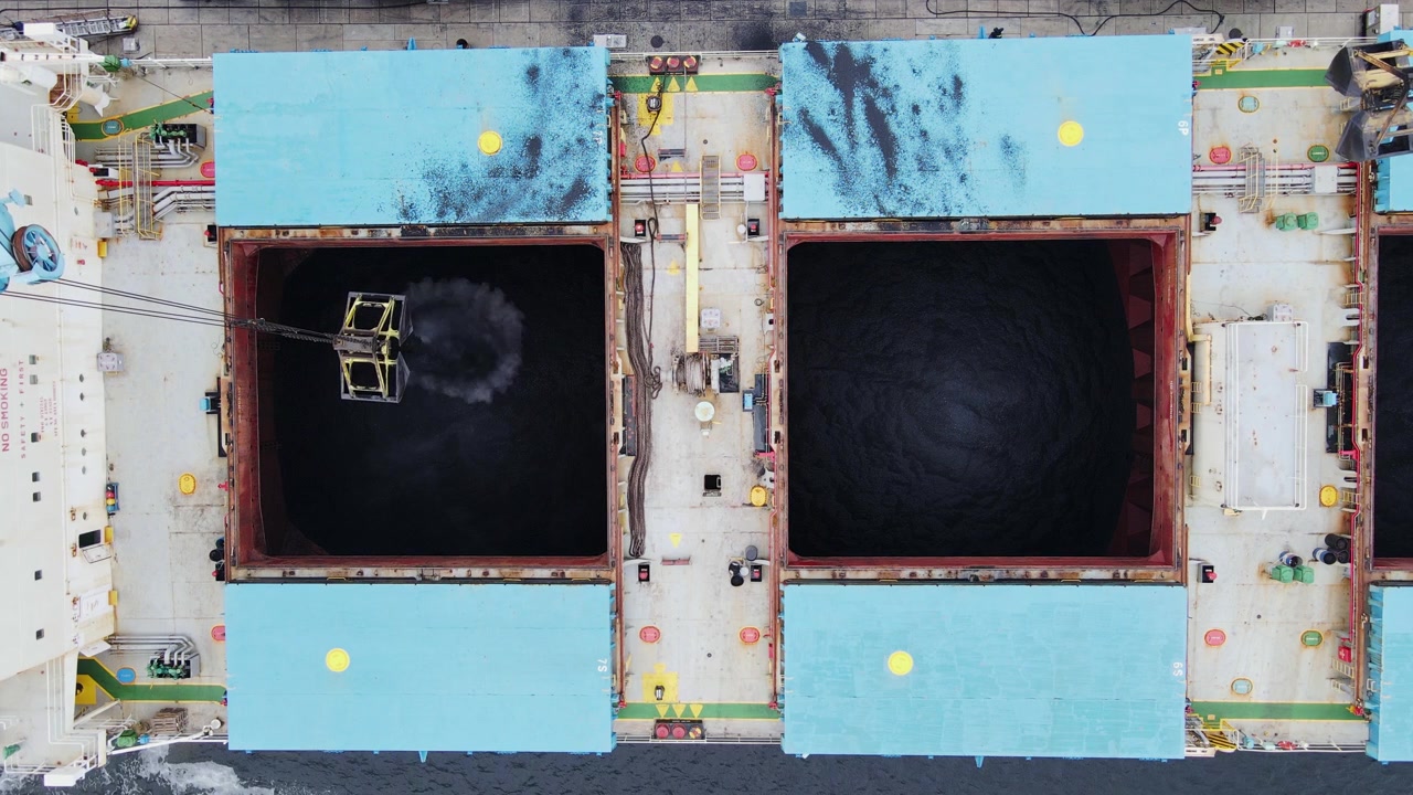 Ripresa aerea con drone del carbone caricato su una nave in un trafficato porto industriale