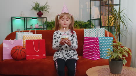 young little children girl sitting on sofa with lots of gifts celebrating birthday party anniversary