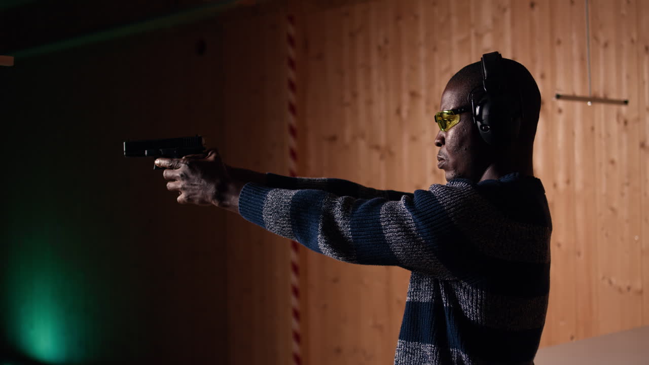 мужчина перезаряжает пистолет во время тренировки с огнестрельным оружием, указывая на оружие