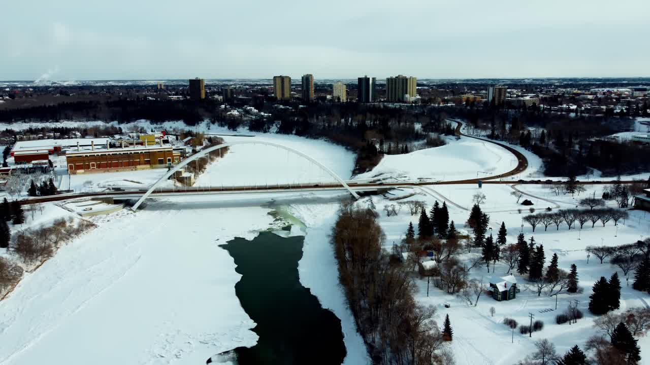vista aérea aérea sobrevuelo invierno cubierto de nieve parcialmente helado río saskatchewan del norte por kinsmen park sports cemter community center vuelo curvo hacia el este norte alrededor del puente walter dale2-3