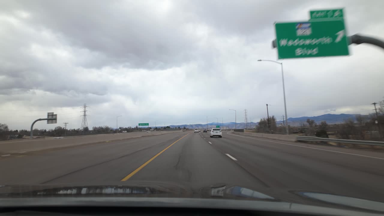 Driving On Colorado's Highway 76 Under Moody Sky With View Of Rocky Mountains In Distance. wide POV shot