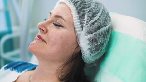 mujer de mediana edad con gorra en la cabeza espera una inyección de botox