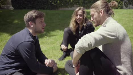 happy young people sitting together on grass