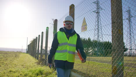 angestellter geht um die elektrische anlage herum und überprüft den sicheren zaun