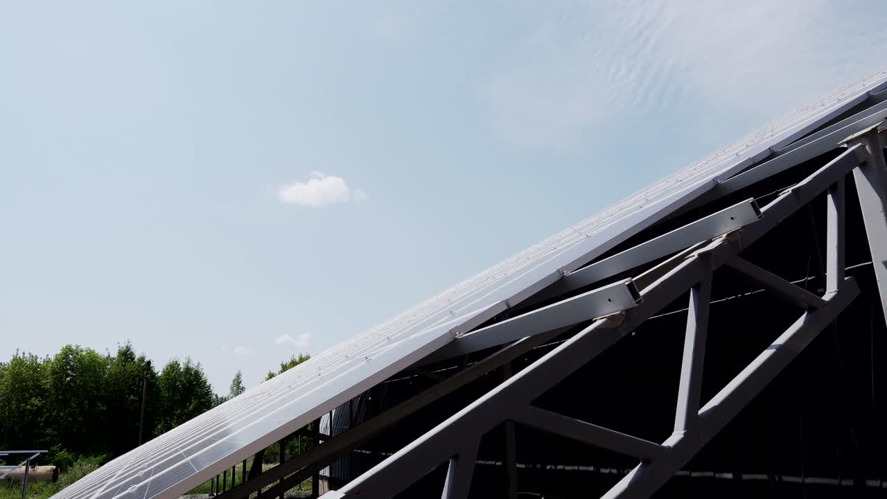 The construction of a large solar panel on a background of green forest and sky. Alternative energy