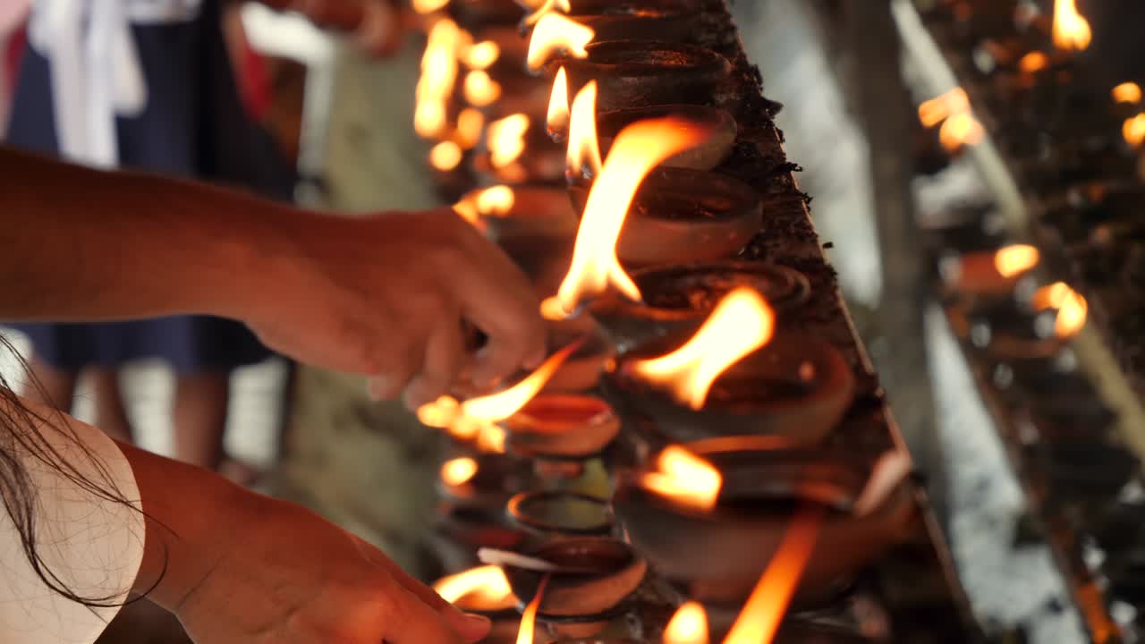 스리랑카의 불교 사원에서 불타는 기름 램프를 켜고 있는 예배하는 사람들의 4k 클로즈업 비디오
