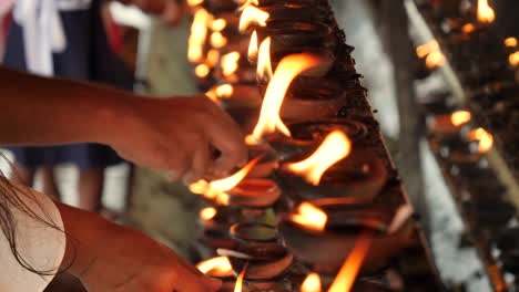 4k closeup video of worshipping people lighting up burning oil lamps in buddhist temple on sri lanka