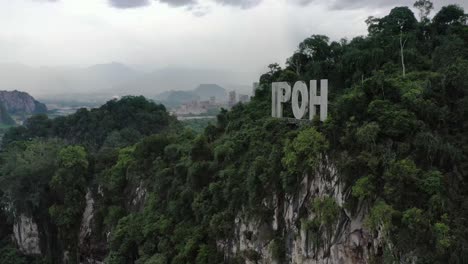 aerial panning shot around the sign of ipoh on top of limestone hill at kawasan perindustrian tasek, perak state, malaysia, southeast asia